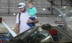 Dad holding son looking into the cockpit of an aircraft at the museum