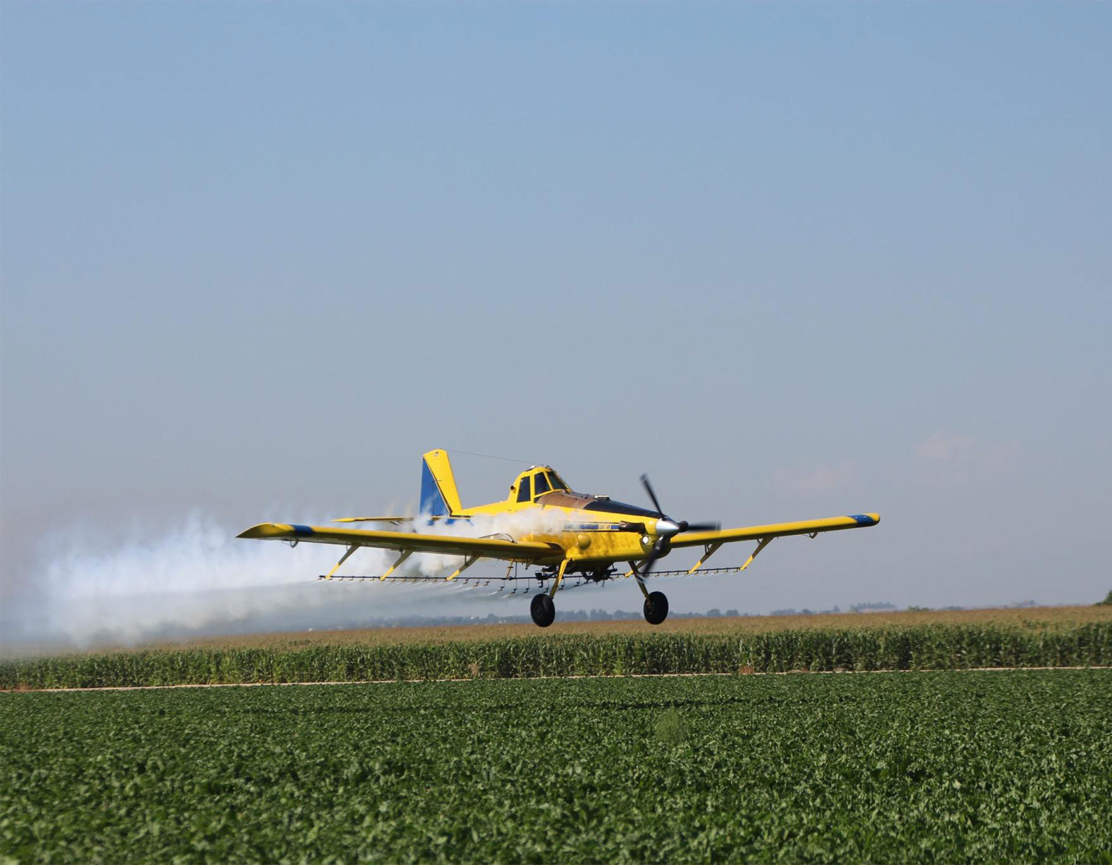 Agricultural aircraft flying low over crops