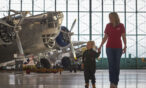 A mom and her daughter holding hands in the hangar