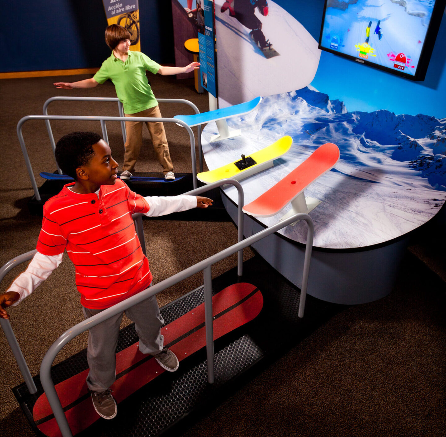 A child is standing on a snowboard simulator.