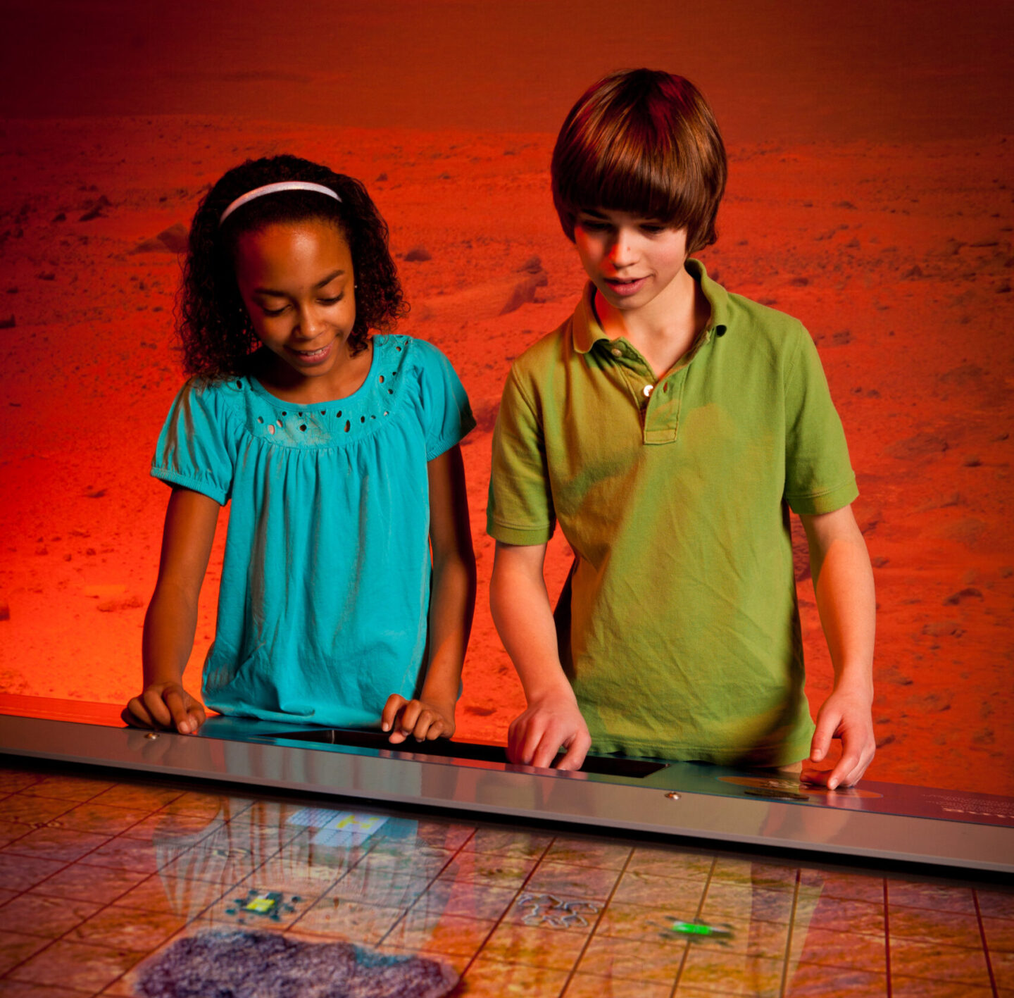 Two children are looking at a Mars Rover simulation.