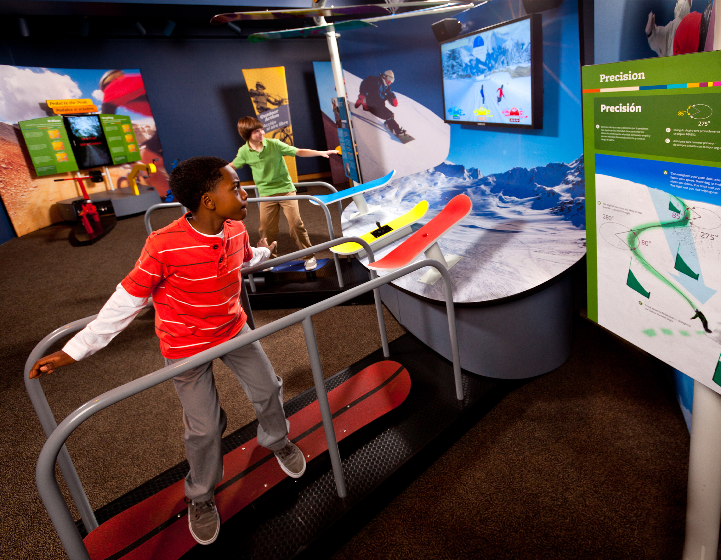 A child is standing on a snowboard simulator in an exhibit.