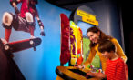 A child and woman are looking at a skateboard exhibit.