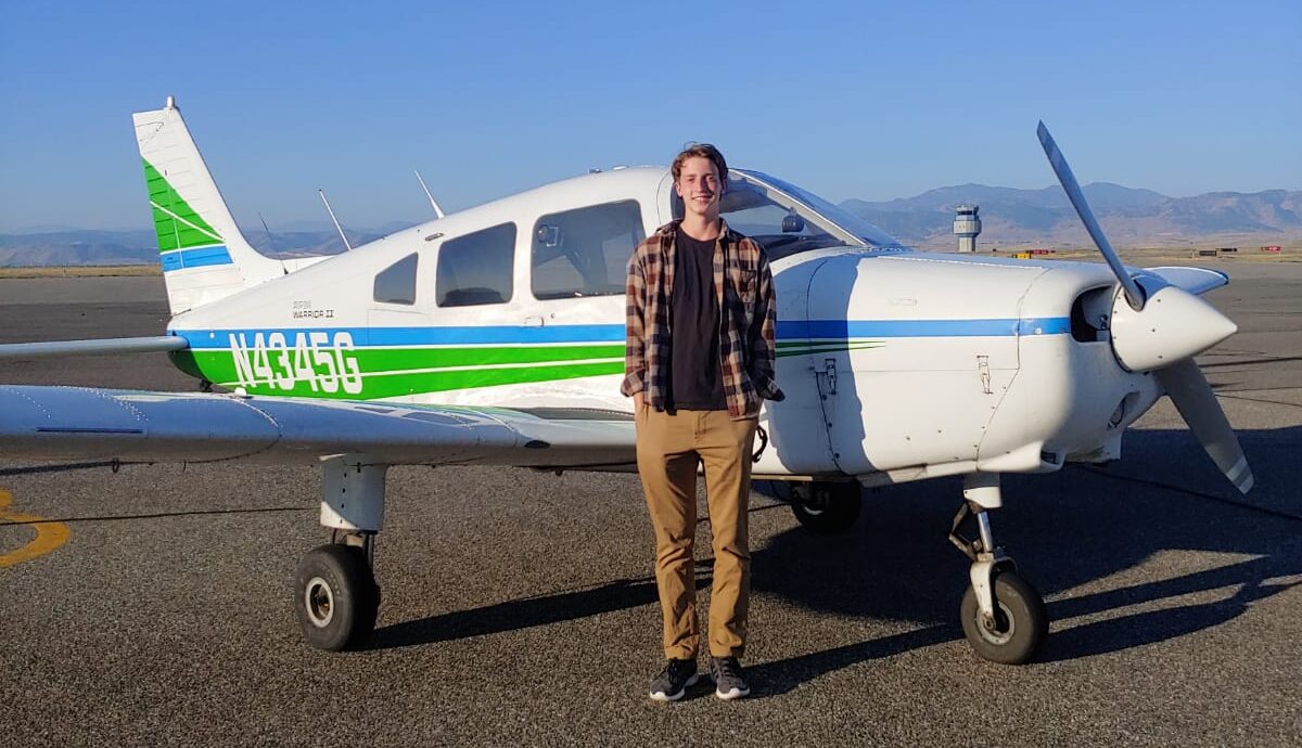 Flight Scholarship Student Ben Hensley smiles next to airplane