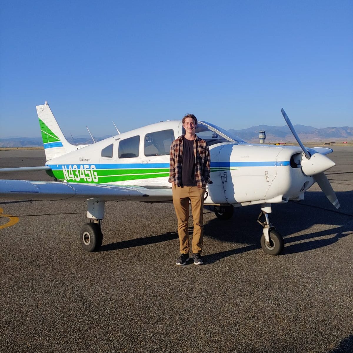 Flight Scholarship Student Ben Hensley smiles next to airplane