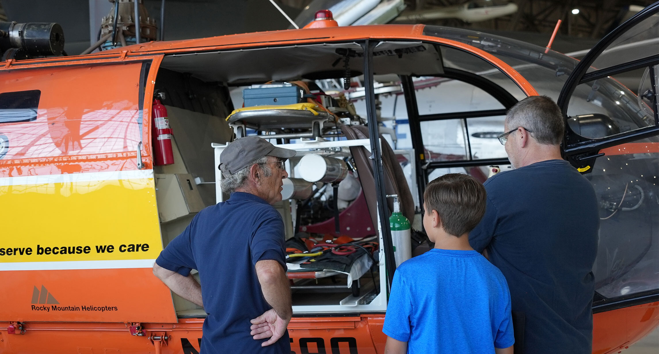 Guests standing with a volunteer looking into the Alouette Helicopter