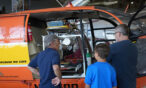 Guests standing with a volunteer looking into the Alouette Helicopter