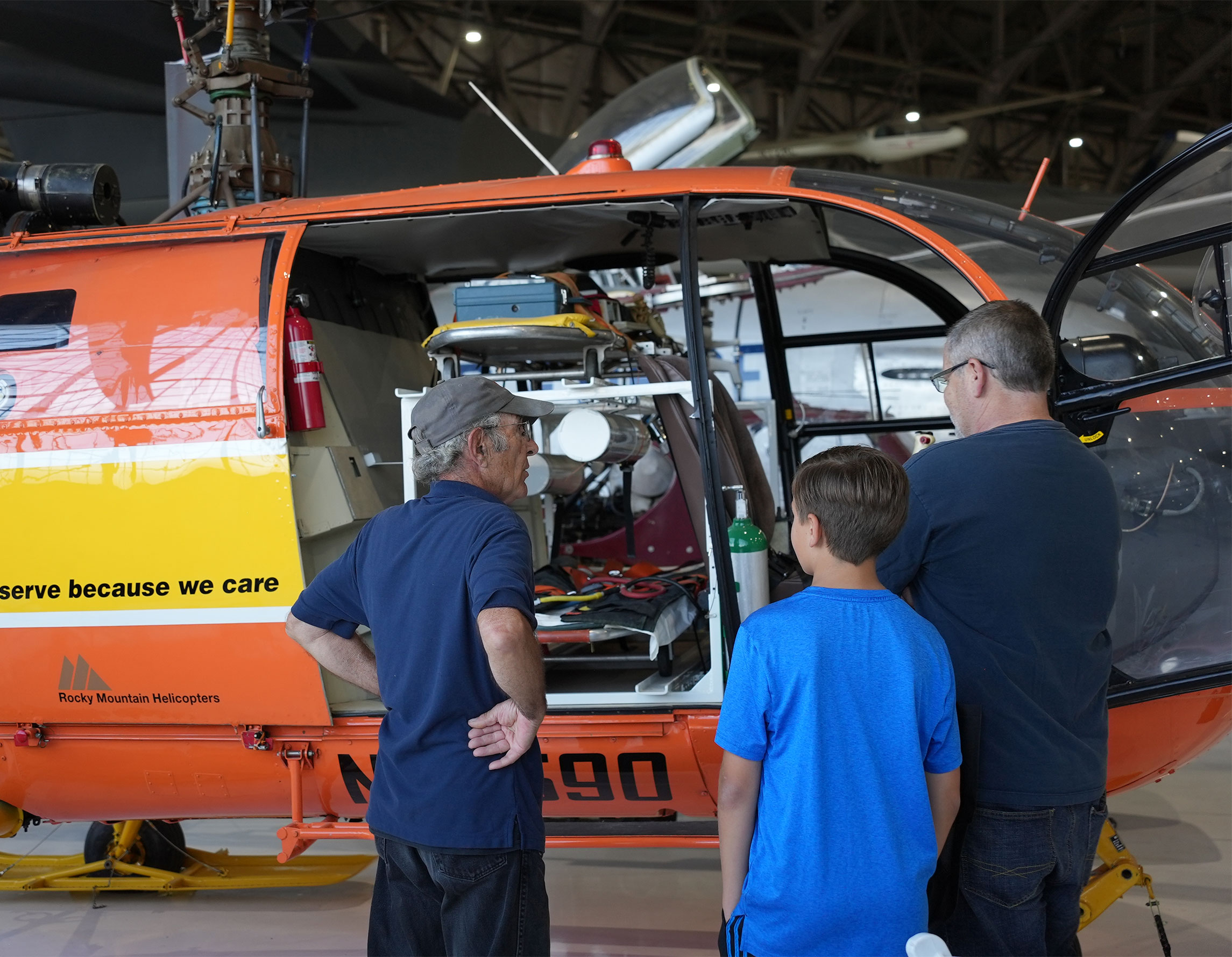 Guests standing with a volunteer looking into the Alouette Helicopter