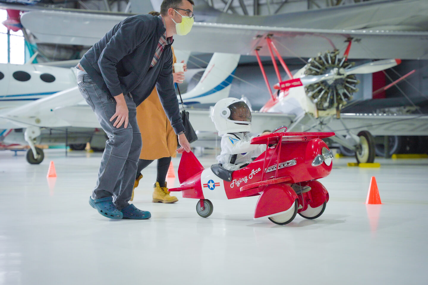 Man pushing boy dressed as an astronaut in a pedal plane
