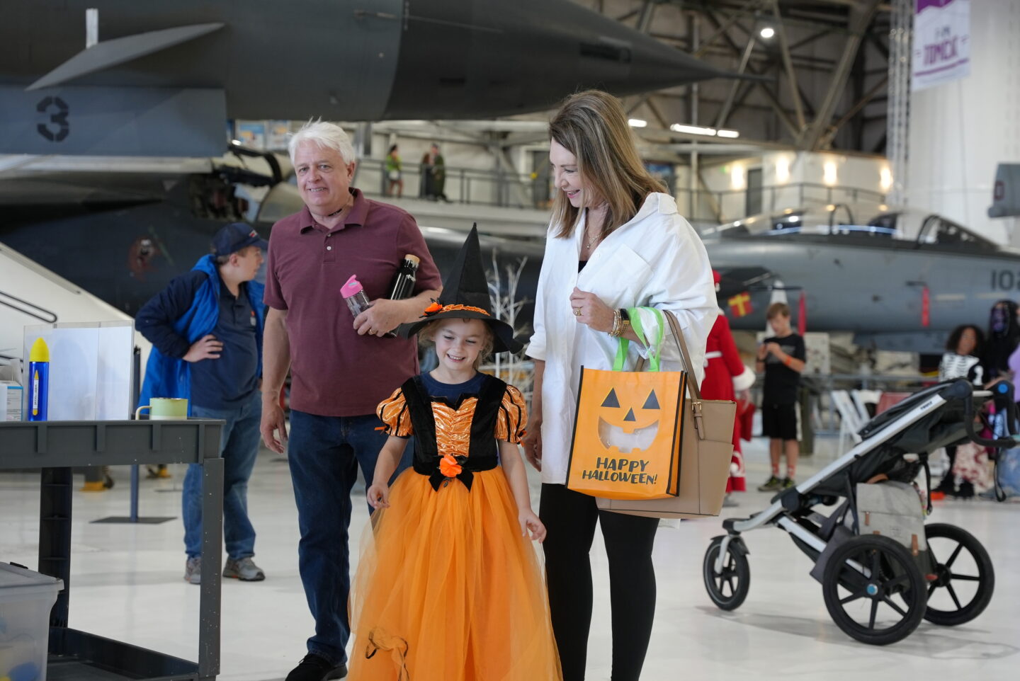 Child in costume with grandparents at Hauntings in the Hangar