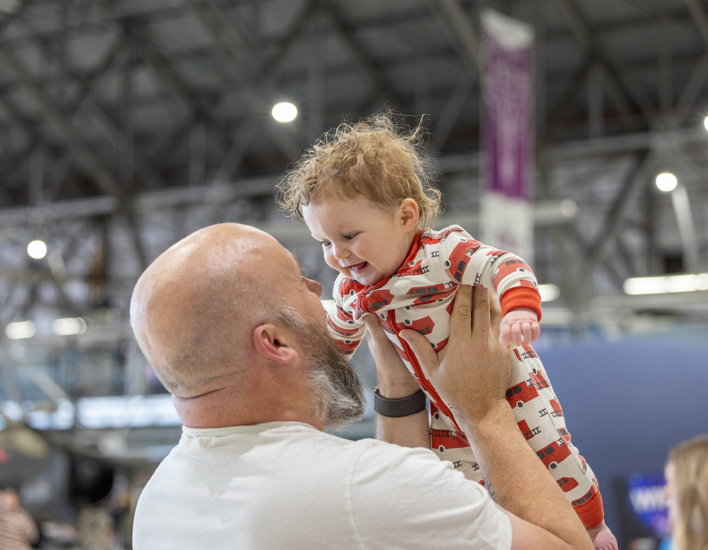 A man and a baby are looking at each other in a hangar.