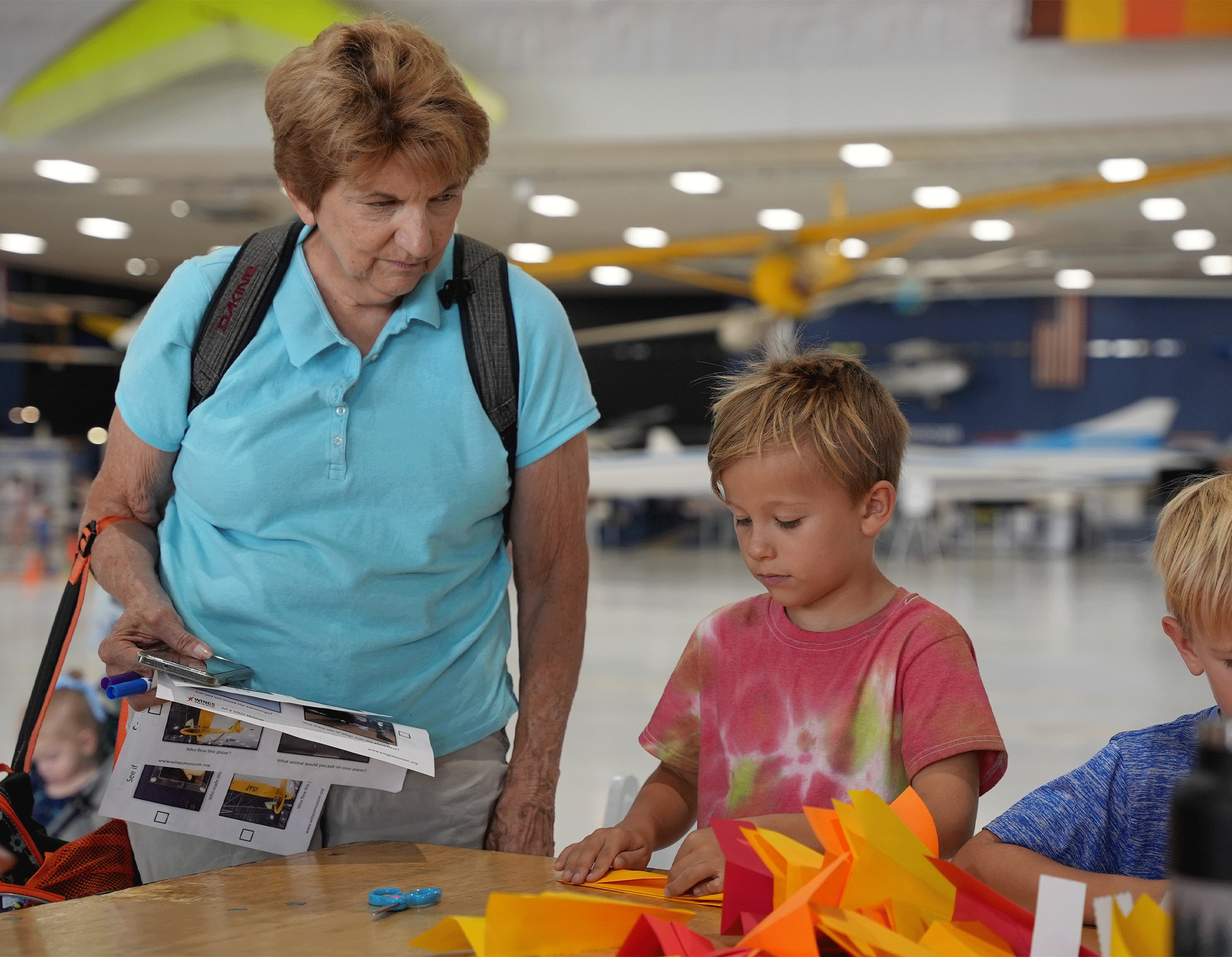 Grandmother & grandson making a paper airplane