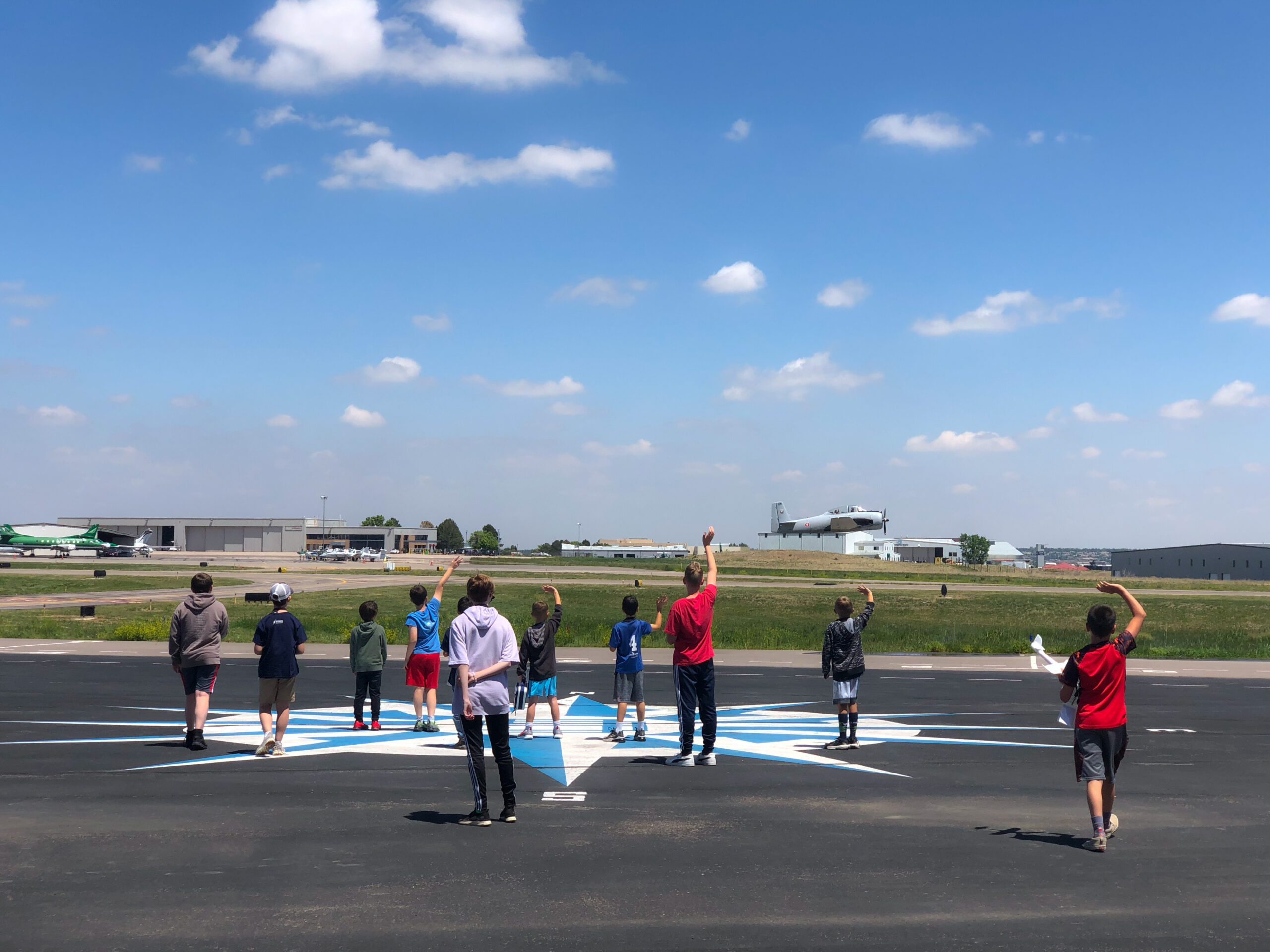 Students waving as an airplane takes off from the runway