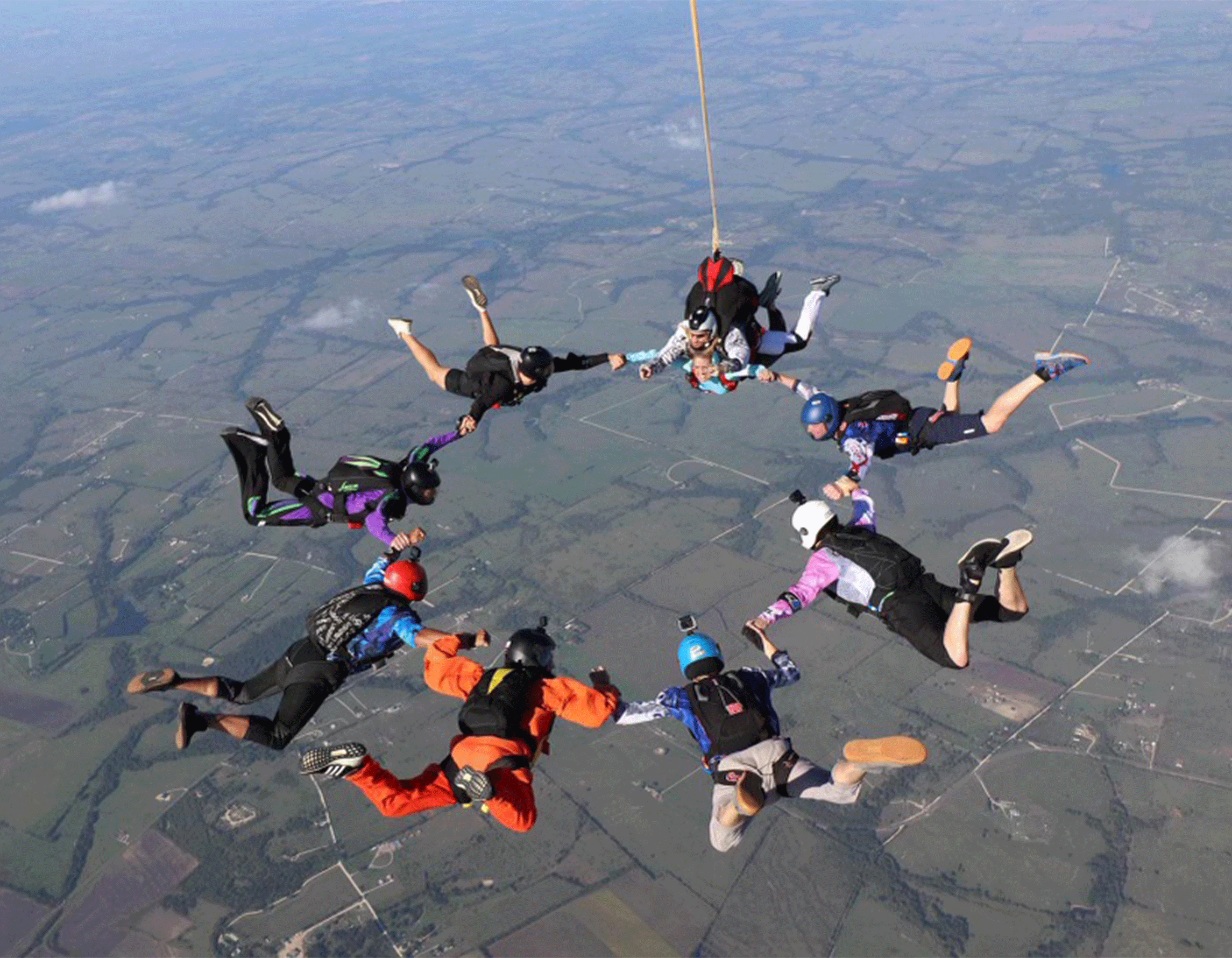 Group of skydivers holding hands in a circle in mid-air