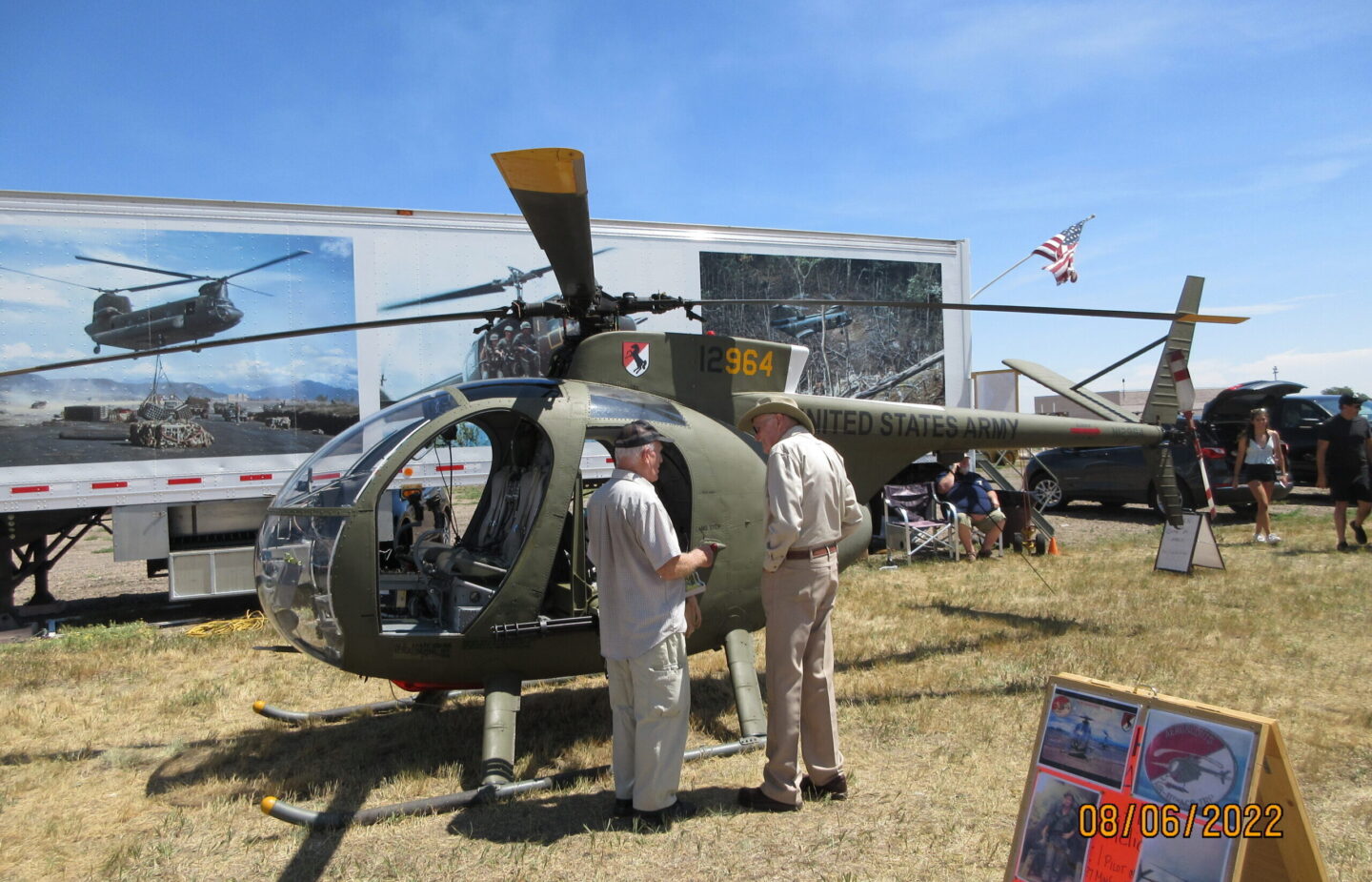 O6 Helicopter displayed on grass field with two suited veterans standing in front