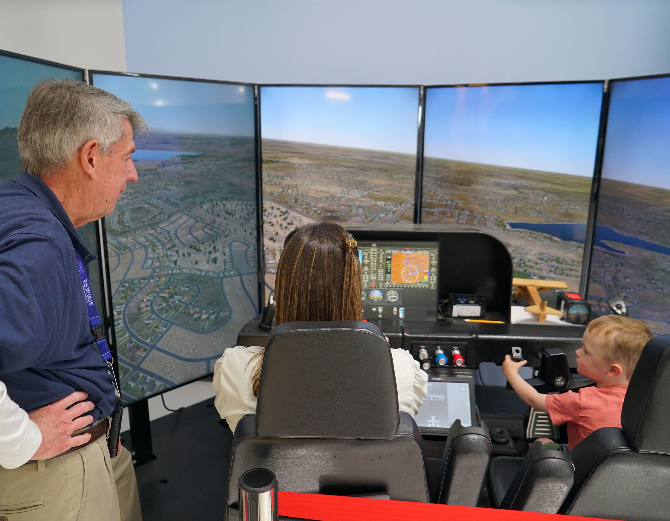 Volunteer teaching Exploration of Flight guests to use the flight simulator