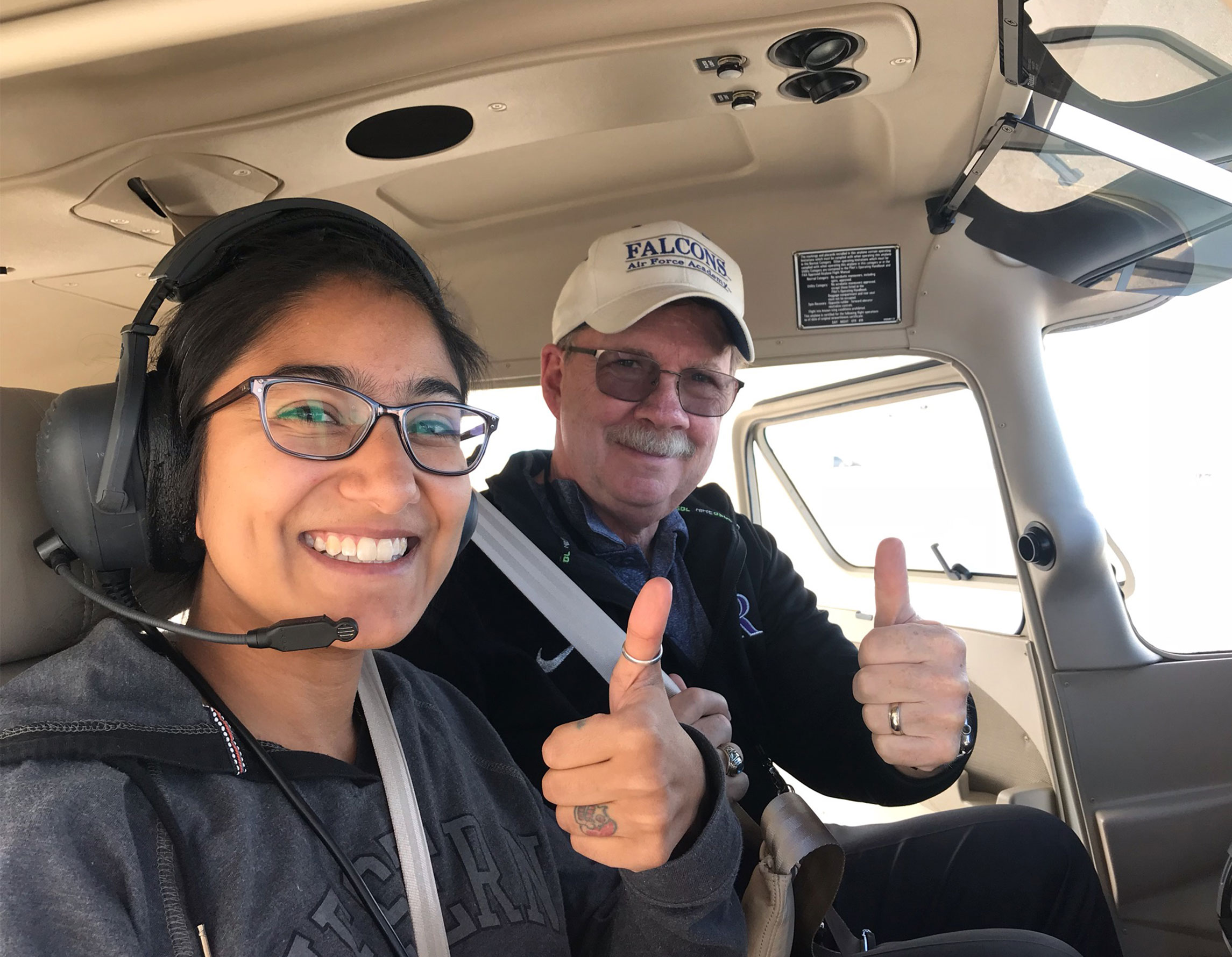 Student and flight instructor give thumbs up in an airplane