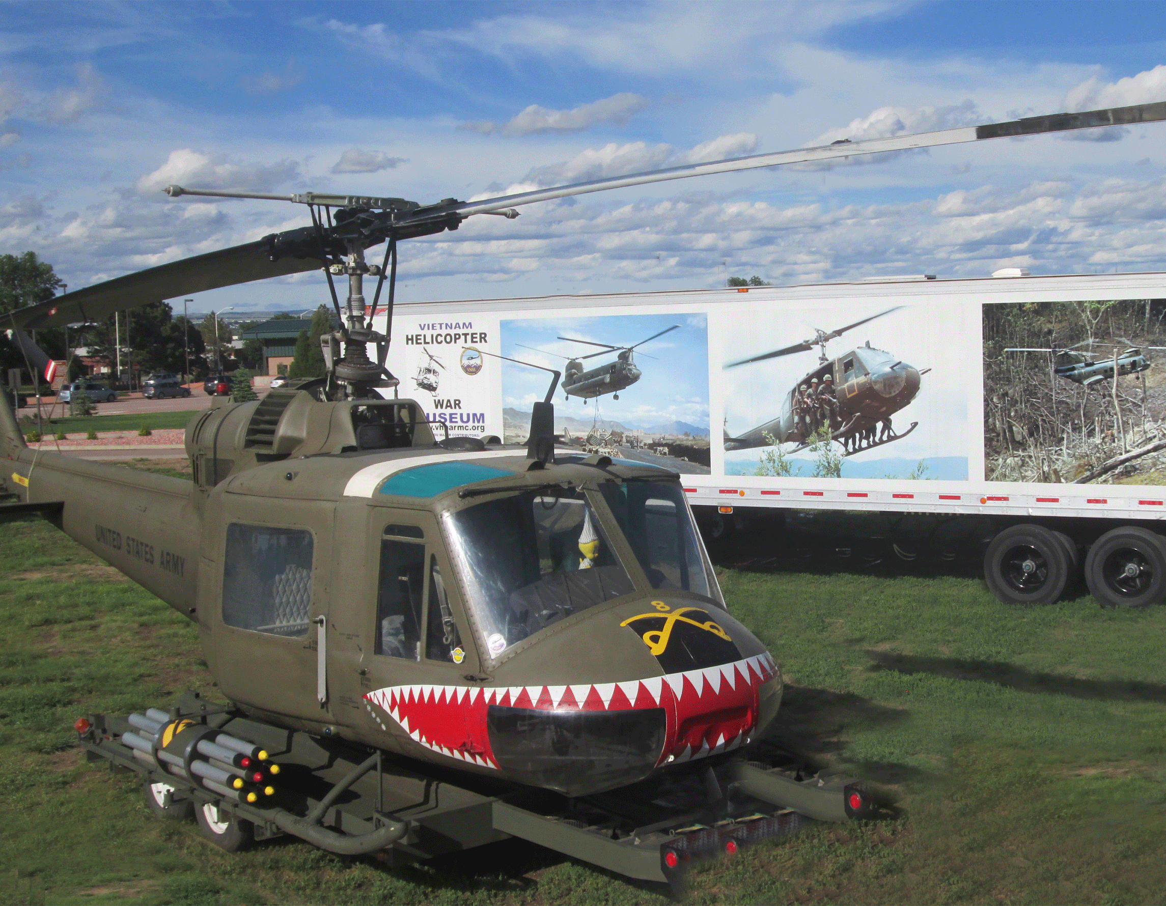 Huey helicopter sitting next to the trailer of the Vietnam Helicopter Museum Exhibit