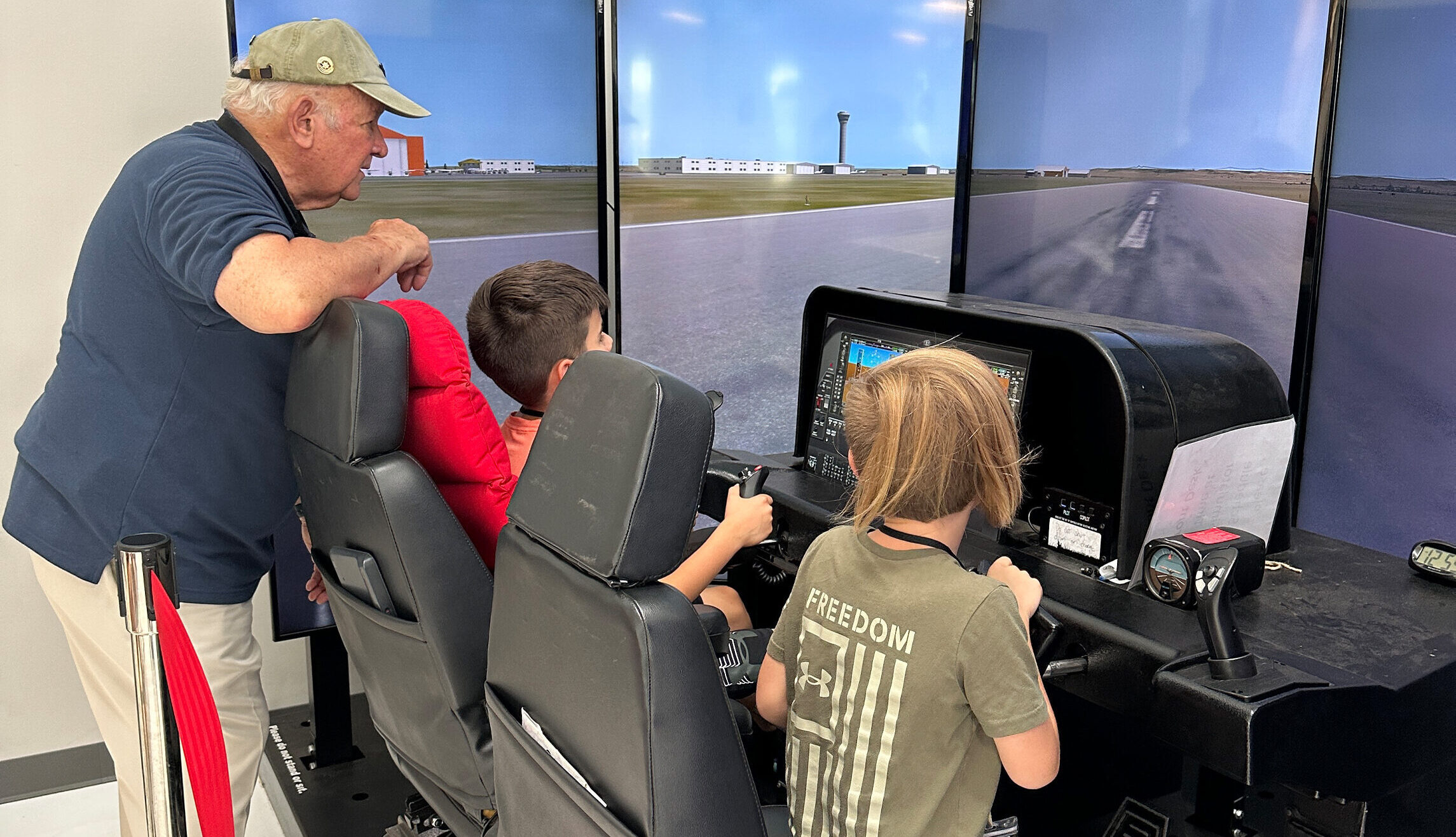 A volunteer and kids are at a simulation. One is holding a handle.