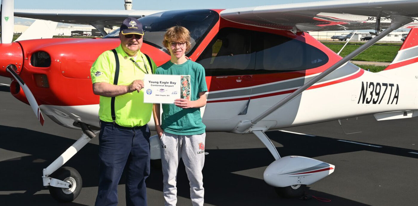 Young Eagles student smiling in front of aircraft with his pilot