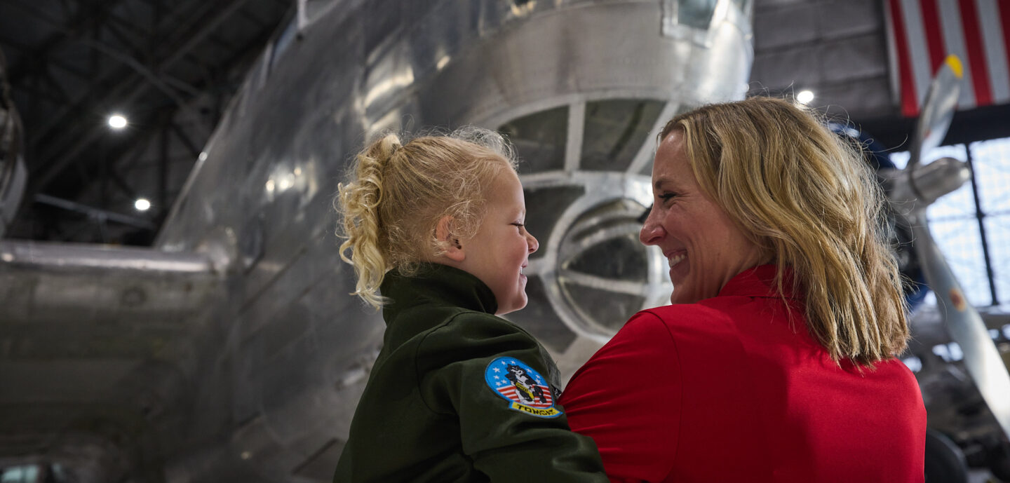 Mom and daughter smiling at each other in front of the B-18A Bolo