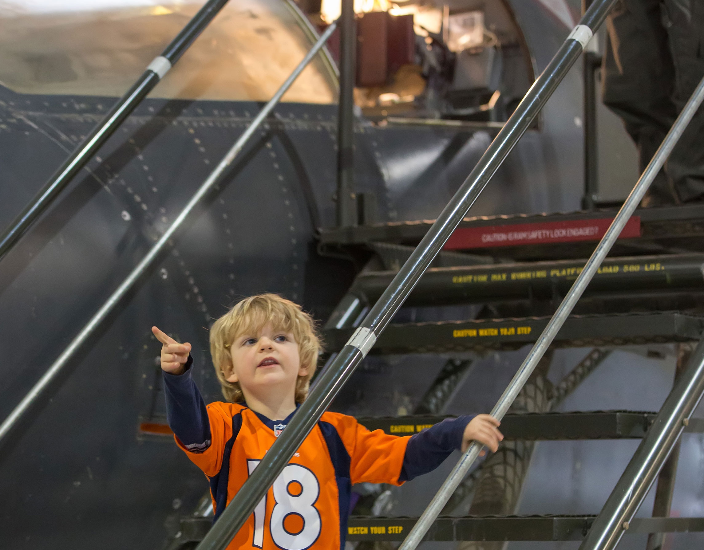 Young boy points up at airplane in the hangar