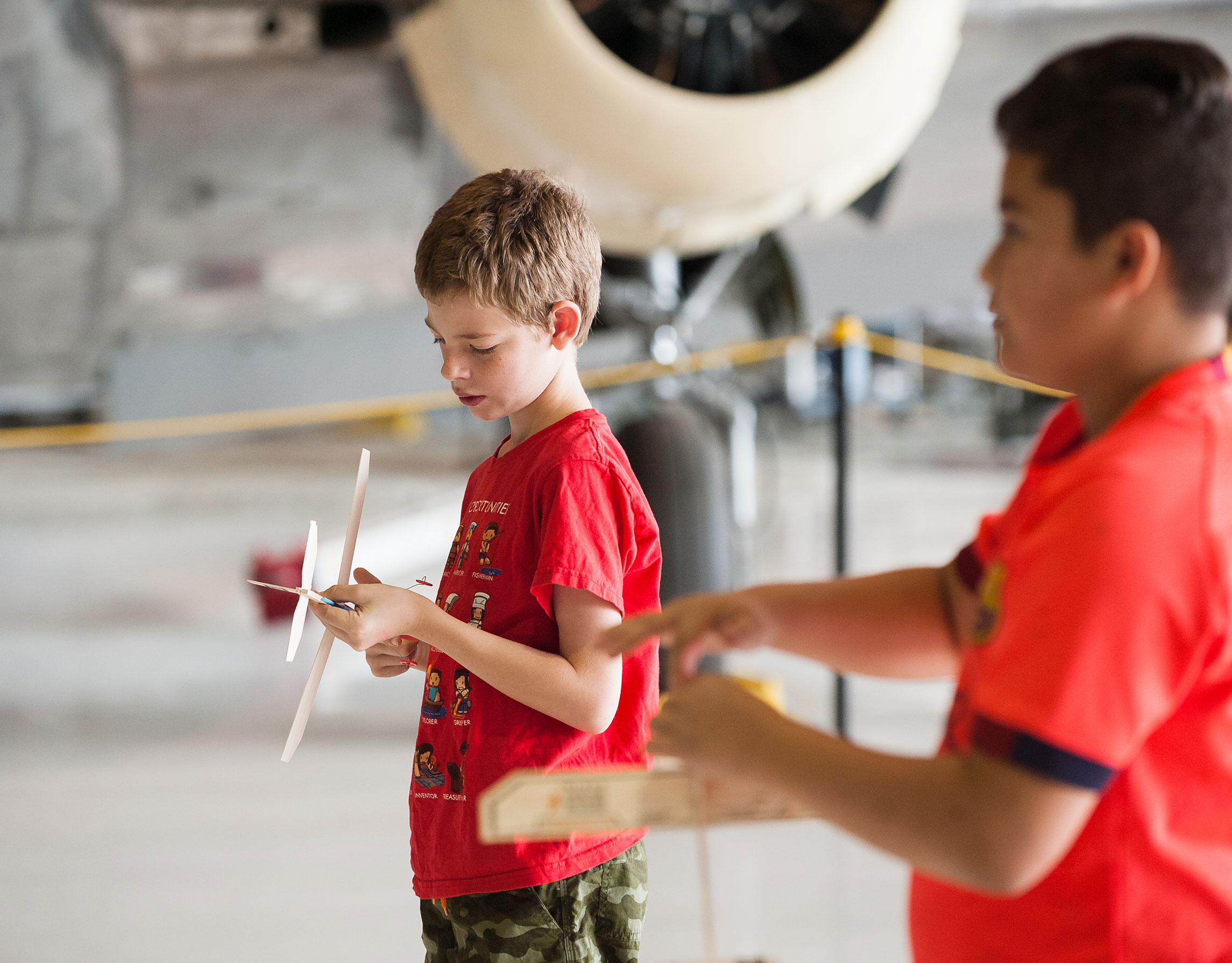 Two young students play with wooden planes they built in the museum's hangar.